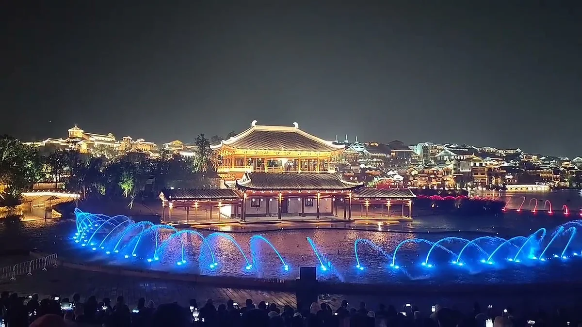 水边古楼夜晚，蓝色喷泉灯光闪烁